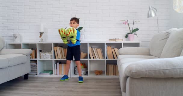 Sześciolatek grający w piłkę nożną z rękawiczkami bramkarza w domu podczas kwarantanny COVID-19. Życie wisi w mieszkaniu. 4k - Materiał filmowy, wideo