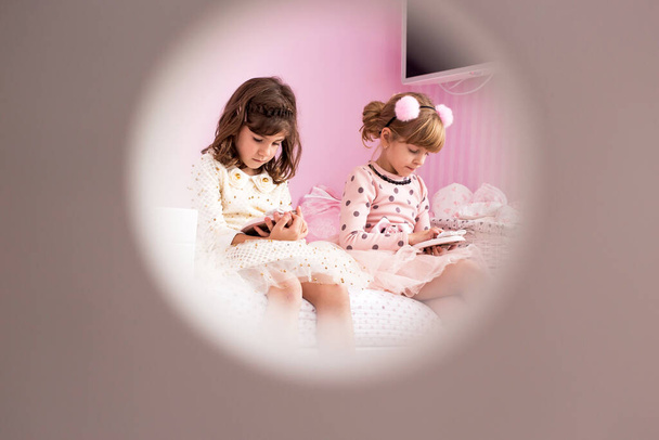 Adorable, cute, little girls, sisters, twins sitting on the bed in their lovely pink room - Foto, Imagen