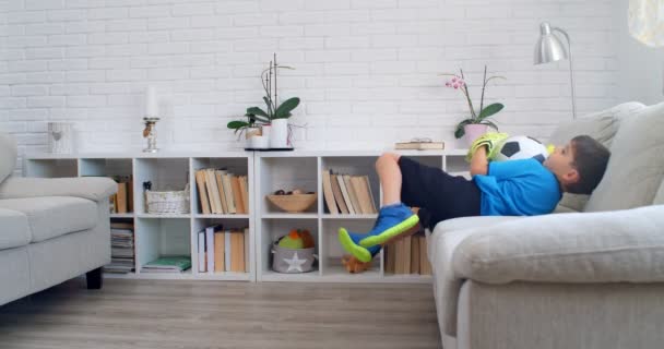 Sześciolatek grający w piłkę nożną z rękawiczkami bramkarza w domu podczas kwarantanny COVID-19. Życie wisi w mieszkaniu. 4k - Materiał filmowy, wideo