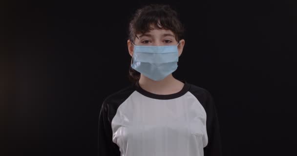 黒の背景に保護マスクとサッカーボールを持つ10代の女の子のサッカー選手の肖像, 4k - 映像、動画