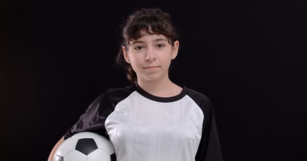 Portret van een tienermeisje voetballer met een voetbal voetbal op zwarte achtergrond, 4k - Video