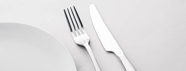 Empty plate and cutlery as mockup set on white background, top tableware for chef table decor and menu branding - Photo, image