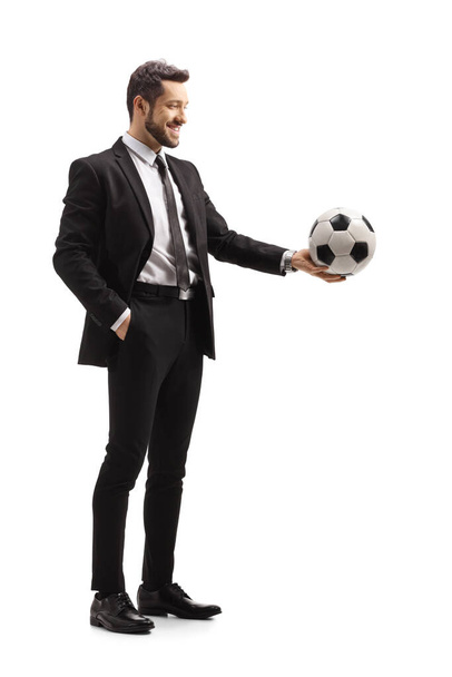 Full length shot of a man in a suit holding a soccer ball isolated on white background - Photo, image