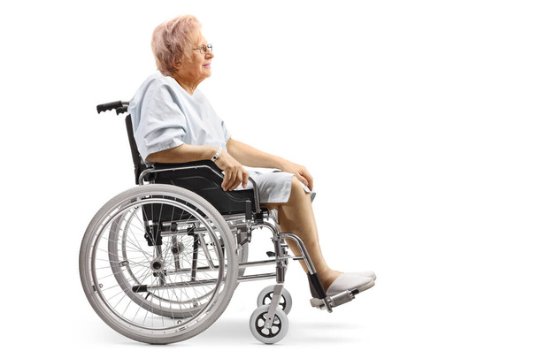 Full length profile shot of an elderly female patient sitting in a wheelchair isolated on white background - Φωτογραφία, εικόνα
