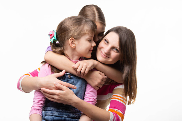 twee zussen en mam zijn knuffelen gelukkig, geïsoleerd op witte achtergrond - Foto, afbeelding