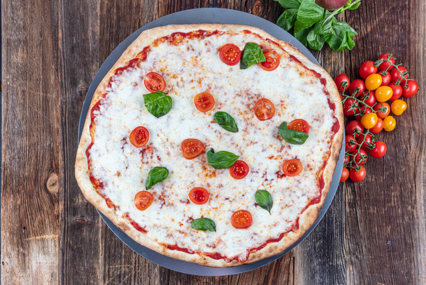 Πίτσα Μαργαρίτα, ιταλική χωριάτικη πίτσα με μοτσαρέλα, τυρί και φύλλα βασιλικού. - Φωτογραφία, εικόνα