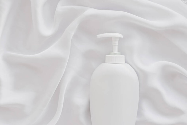 Tyhjä etiketti kosmeettisia säiliö pullo tuotteen mockup valkoisella silkki tausta
 - Valokuva, kuva