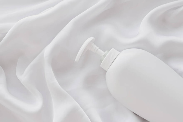 Beyaz ipek arka planda ürün modeli olarak boş etiket kozmetik kutu şişesi - Fotoğraf, Görsel