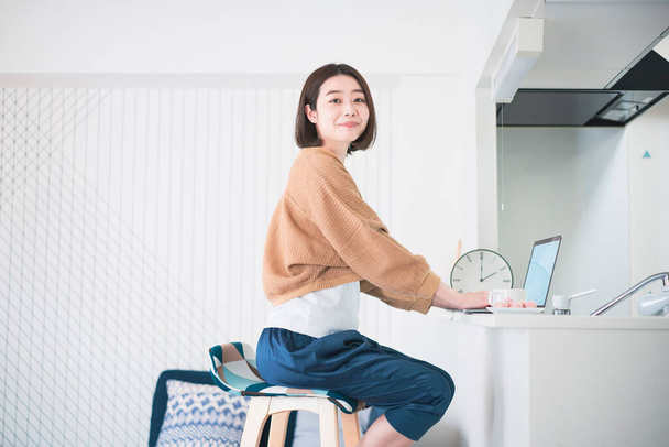 Asiática jovem mulher trabalhando remotamente com laptop no quarto em casa
 - Foto, Imagem