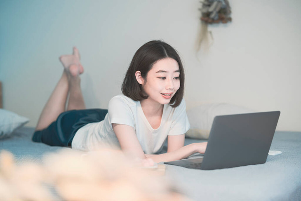 Asiática joven mujer mirando a la pantalla del ordenador portátil en la habitación en casa
 - Foto, Imagen