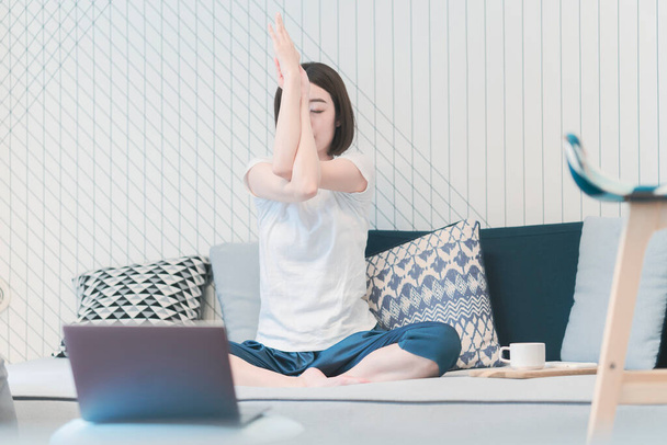 Young Asian woman taking an online yoga lesson in the living room - 写真・画像