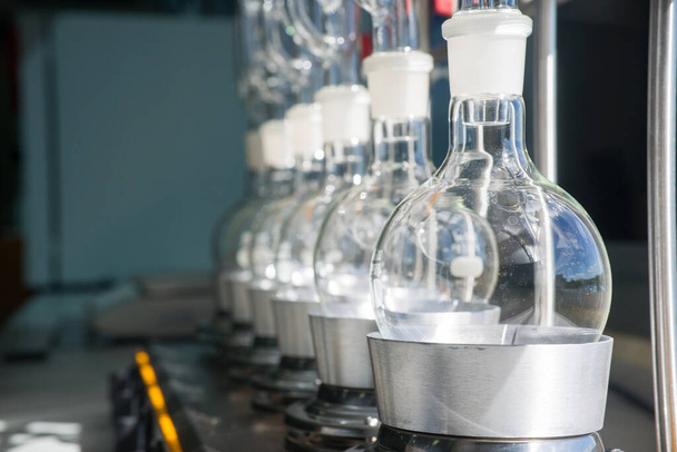 Equipo de laboratorio, botellas de vidrio, matraz inferior redondo en el manto de calefacción, extracción de Soxhlet
 - Foto, imagen