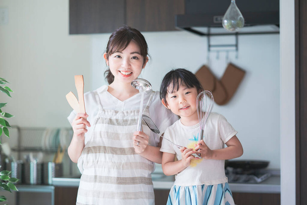 Ázsiai fiatal anya és lánya kihívás főzés konyhai eszközökkel - Fotó, kép