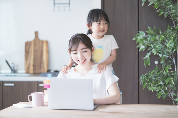 aziatische vrouw doet telewerk in home room terwijl spelen met haar dochter - Foto, afbeelding
