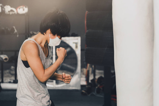 ásia mulher vestindo médico máscara formação boxe com perfuração saco no ginásio e fitness club
 - Foto, Imagem