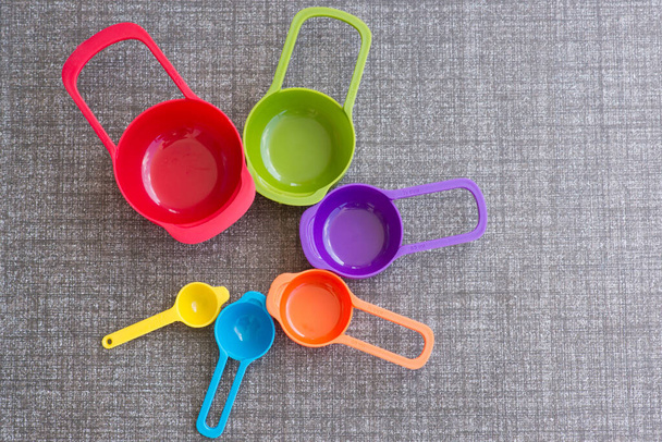 Colorful measuring cups on kitchen floor. - Zdjęcie, obraz