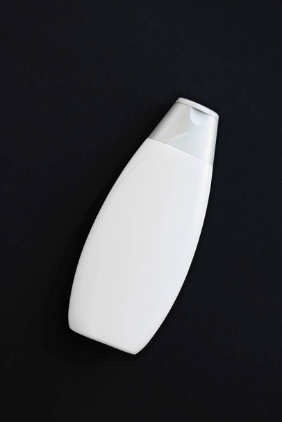 Etiqueta en blanco botella de envase cosmético como maqueta del producto sobre fondo negro
 - Foto, imagen