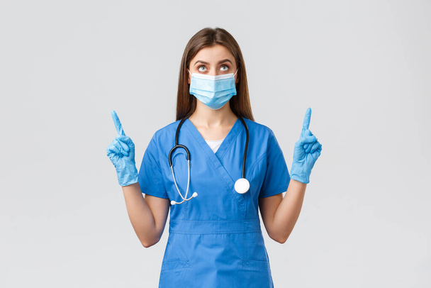 Covid-19 、ウイルス、健康、医療従事者および検疫の概念を防止する。青い頭皮で好奇心旺盛な女性医師や看護師,医療用マスク読書バナー,指差し指 - 写真・画像