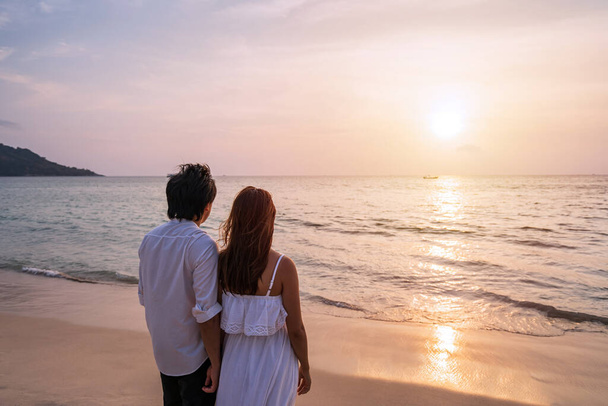 Young asian couple looking beautiful sunset on the beach, Summer vacation concept - Foto, Bild