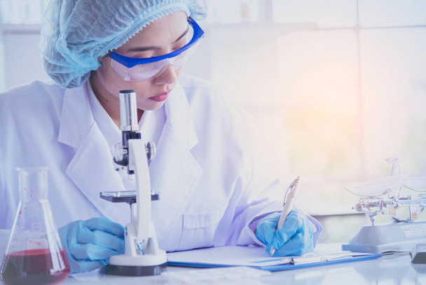 Cientista feminina olhar para o microscópio, tubo de teste de ciência analisar amostra científica em laboratório experiência biotecnologia fazer cultivar a vacina contra o vírus. Conceito de laboratório de química - Foto, Imagem
