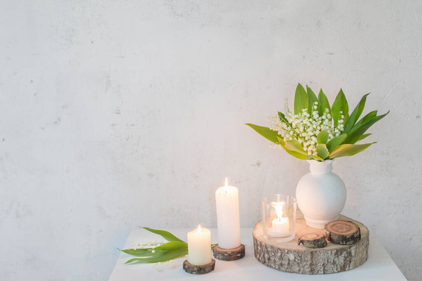 lily of the valley in vase with candles on background old white wall - Fotografie, Obrázek