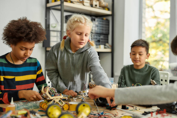 Finding solutions. Three kids building robots and vehicles at robotics lesson. Smart children and STEM education. - Fotoğraf, Görsel
