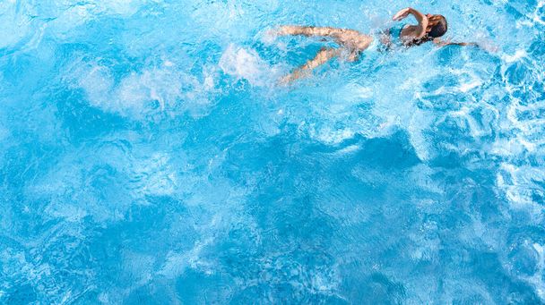 Active girl in swimming pool aerial drone view from above, young woman swims in blue water, tropical vacation, holiday on resort concept - 写真・画像