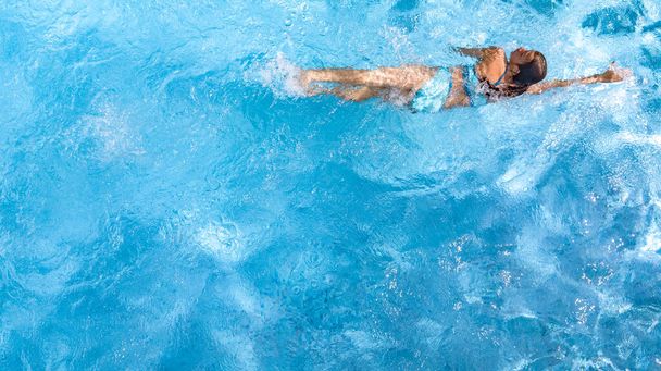 Active girl in swimming pool aerial drone view from above, young woman swims in blue water, tropical vacation, holiday on resort concept - 写真・画像