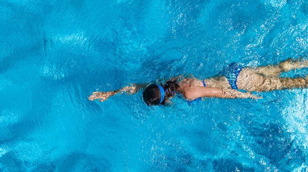 Active girl in swimming pool aerial drone view from above, young woman swims in blue water, tropical vacation, holiday on resort concept - Zdjęcie, obraz