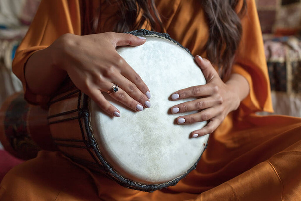 de handen van het meisje spelen een prachtige melodie op een Afrikaanse drum. meditatie. - Foto, afbeelding