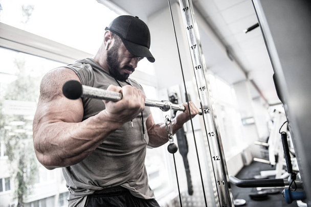 sport mental mind concentration of strong young bearded man training big muscle using fitness equipment during heavy workout exercise listening music for drive - Foto, Imagen