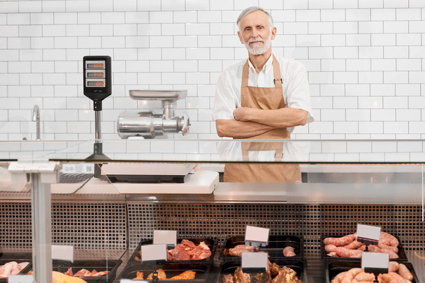 Male butcher posing behind counter. - Foto, Bild