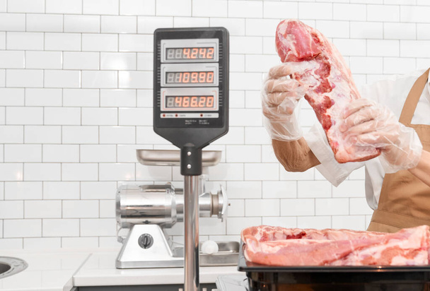 Incognito male butcher demonstrating meat. - Zdjęcie, obraz