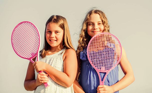 Rest time. sporty game playing. summer outdoor games. play tennis. childhood happiness and sisterhood. small girls with tennis racquet. summer sport activity. energetic children. happy and cheerful - Photo, image