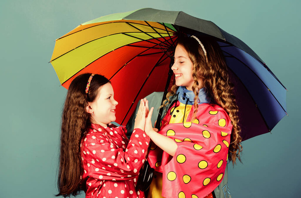 cheerful hipster children, sisterhood. rain protection. Rainbow. family bonds. Little girls in raincoat. happy little girls with colorful umbrella. autumn fashion. Carefree morning - Photo, image