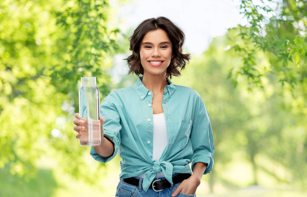 smiling young woman holding water in glass bottle - Foto, imagen