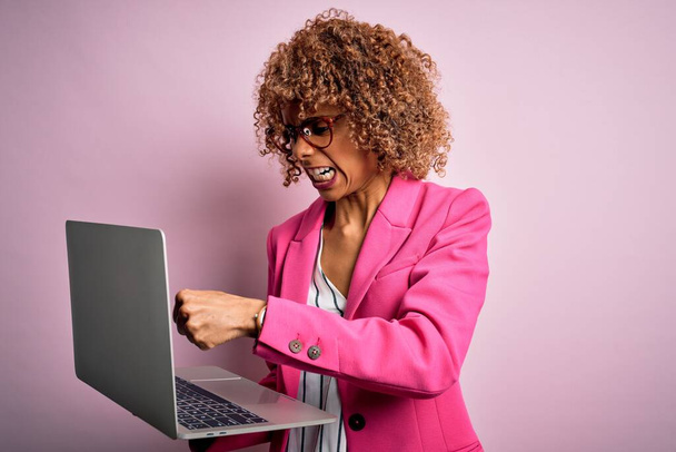 African american business woman with curly hair working using laptop over pink background annoyed and frustrated shouting with anger, crazy and yelling with raised hand, anger concept - Fotó, kép