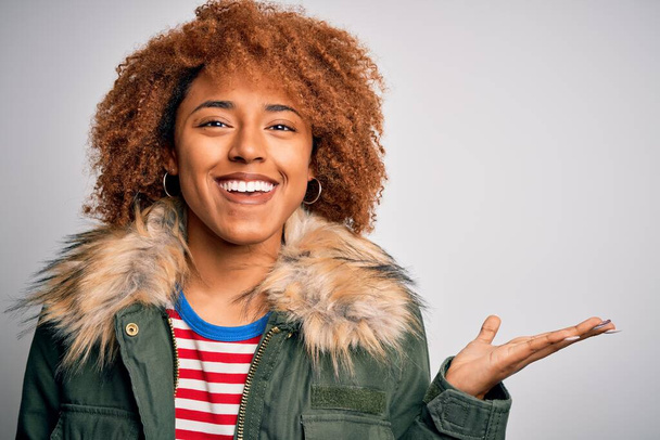Young beautiful African American afro woman with curly hair wearing casual winter coat very happy and excited, winner expression celebrating victory screaming with big smile and raised hands - Φωτογραφία, εικόνα