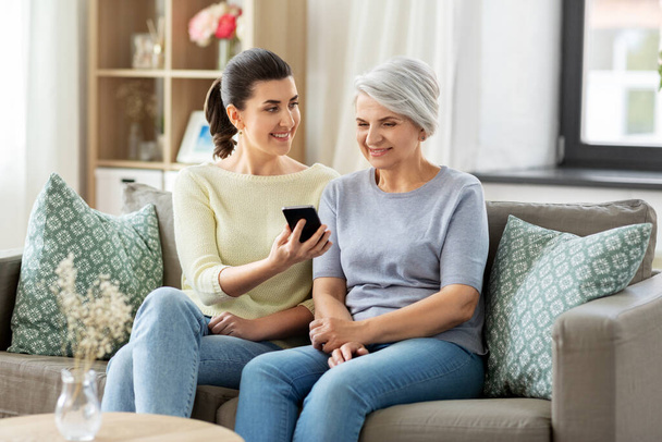 daughter and senior mother with smartphone at home - Foto, Bild