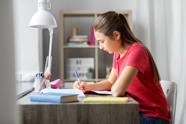 student girl with book writing to notebook at home - Photo, Image