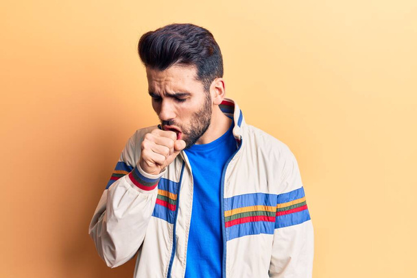 Young handsome man with beard wearing casual jacket feeling unwell and coughing as symptom for cold or bronchitis. health care concept.  - Photo, Image