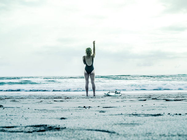 jonge vrouw in badpak staan op het strand - Foto, afbeelding