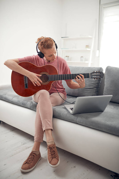 Гітарист дивиться онлайн відео уроки та підручники з ноутбука
. - Фото, зображення