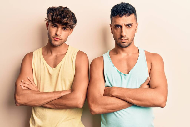 Mladý gay pár v neformálním oblečení skeptický a nervózní, nesouhlasný výraz na tváři se zkříženýma rukama. negativní osoba.  - Fotografie, Obrázek