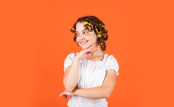 Child making hairstyle. little happy girl with curlers in hair. fabric mask under eyes for beauty. cute kid standing with patches under eyes. Child fashion model concept. Curled hair with braid. - Foto, Imagem