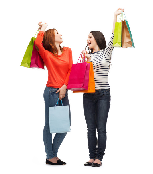 twee glimlachend tienermeisjes met shopping tassen - Foto, afbeelding