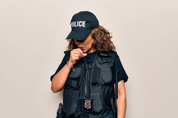Középkorú gyönyörű rendőrnő visel golyóálló egyenruha és sapka felett fehér háttér rossz közérzet és köhögés tüneteként hideg vagy hörghurut. Egészségügyi koncepció. - Fotó, kép