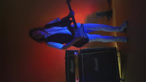 Κάθετος κιθαρίστας του video rock που παίζει κιθάρα στο Studio υπό το φως προβολέων και καπνού - Πλάνα, βίντεο