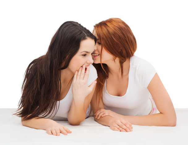 Two smiling girls whispering gossip - Фото, изображение
