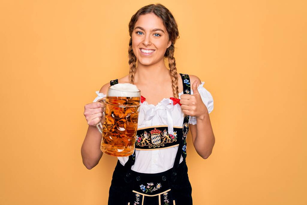 Mavi gözlü, güzel, sarışın Alman kadın, Ekim Festivali elbisesi giyiyor, bira kavanozu içiyor, gülümsüyor ve gülümsüyor. - Fotoğraf, Görsel